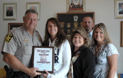 Megan Woodard receives a $750 scholarship from Calvert Sheriff Evans. Pictured left to right are Sheriff Evans, Megan Woodard, Jackie Weston (grandmother), Christine Tomlinson (mother), and Mike Tomlinson (father). (Submitted photo)
