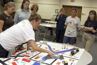 Elementary and middle school teachers watch as Karin Stewart, STEM teacher specialist for Calvert County, explains the Robotics Challenge course and how it will be used in competition. In addition to programming their Lego robot to complete tasks as it moves around the course, students will be judged on how well they work as a team. (Submitted photo)
