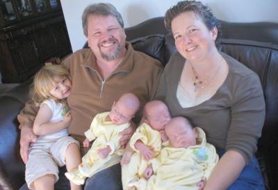 Dave and Lori Titus proudly display their newly expanded family. From left, Rowan Titus, Arthur Titus, Brannon Titus and Charles Titus rest comfortably in their parents' arms. (Photo: Jenn Bogdan, Capital News Service)
