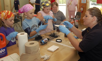 Crime Lab Technician Summer Porter, right, demonstrates fingerprinting techniques to Girl Scouts, from left, Sammi Youman, Kim Knight and Molly Morgan at the Girl Scout’s Crime Scene Investigation event at Camp Winona. (Submitted photo)