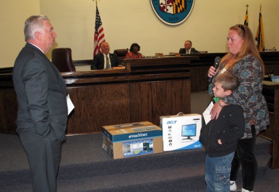 Richard (Dick) Aldridge presents a new computer to Michelle Fox at a recent Charles County Commissioners meeting. Fox works three part-time jobs and attends CSM, while raising a family. The PC will help her complete her coursework at home. (Photo: George Clarkson)