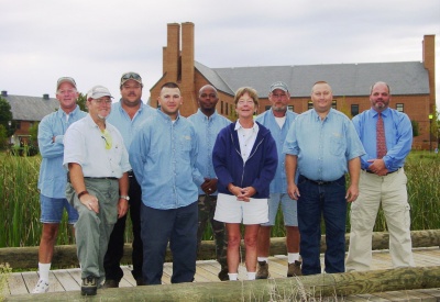 St. Mary's College of Maryland's Audubon-certified grounds crew includes (from left) George Lancaster, James Dyson, Steve Gregory, Kevin Duffy, Eric Reed, Cheryl Krumke, Chris McKay, Rick Thompson and Superintendent of Grounds Kevin Mercer. They are standing on a bridge over a habitat sanctuary created from a storm water management pond once surrounded by nothing but dirt and in front of Goodpaster Hall, which won a silver rating from the Leadership in Energy and Environmental Design's (LEED) green building rating system. (Submitted photo)