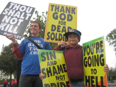 Cousins and Westboro Baptist Church members Jacob Phelps, 27, and Daniel Phelps, 9, stand outside the Supreme Court with anti-gay protest signs. Capital News Service Photo by Jon Aerts.