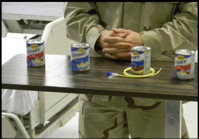 Military medical personnel explain the process of force-feeding the dietary supplement Ensure to prisoners on hunger strikes. (Photo: Laura Lee)