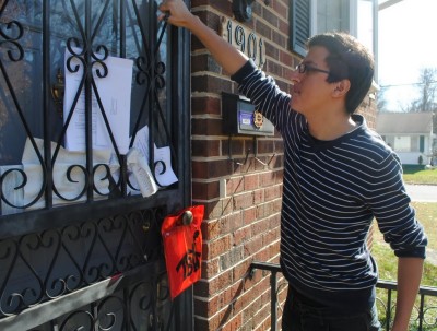 After attaching an information baggie, Gabriel Rodriguez-Rico gives a final try to a metal door in hopes that he might reach a homeowner. (Photo: Jeffrey Benzing)