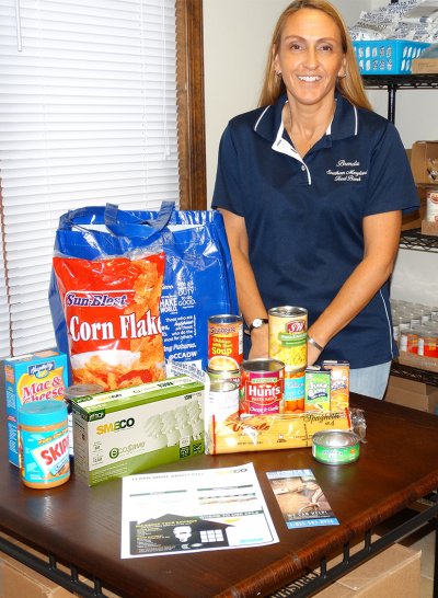 Brenda DiCarlo, Southern Maryland Food Bank Director, shows what an average family would receive for assistance from the food bank. Having operated for 31 years, the food bank distributes needed supplies to families in Calvert, Charles, and St. Mary's counties and is now serving approximately 11,500 families each month. (Submitted photo)