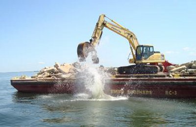 Concrete rubble is pushed into the bay from a barge in order to create an artificial reef. (Photo: Sarah Miller)