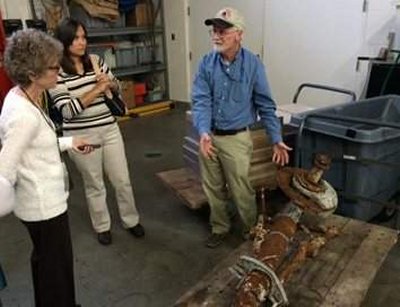 In the pre-treatment area of the Maryland Archaeological Conservation Lab, NAS Patuxent River Cultural Resources Manager Mike Smolek explains that the first steps in the conservation process of the recovered A-1 Skyraider landing gear are cleaning, desalination and coating. (U.S. Navy photo by Shawn Graham)