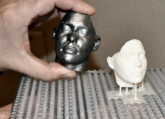 A mini-replica of a human head created with 3D Printing Technology is demonstrated during a December Print-A-Thon at NSWCDD. The reality of 3D Printing - also known as additive manufacturing - is expanding across the Navy's science and engineering community via Naval Surface Warfare Center Dahlgren Division (NSWCDD) and Combat Direction Systems Activity (CDSA) Dam Neck. (U.S. Navy photo by Luefras Robinson/Released)