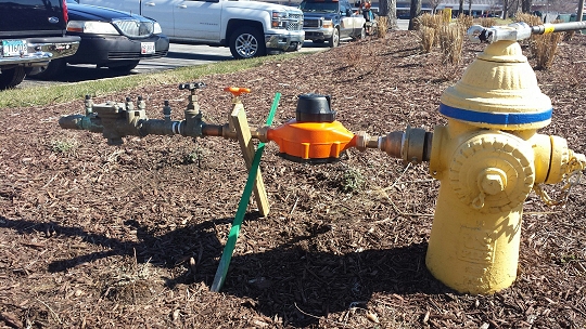 Photo shows an orange Charles County hydrant meter with a backflow preventer.