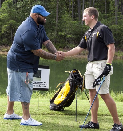 Retired Redskin offensive lineman Tre’ Johnson, left, shakes hands with CSM sophomore and golf team member George Bowie at the sixth hole at Swan Point Yacht and Country Club on Aug. 15. The hole was dedicated to the memory of Eric Sawchak, a CSM student-athlete, who lost his battle with cancer during the CSM golf team’s 2013 season. CSM President Dr. Brad Gottfried announced that $1,000 of the Golf Classic’s proceeds would fund the Eric Sawchak “Longest Drive” Memorial Scholarship to support future student-athletes attending CSM. Bowie, who graduated from McDonough High School was on the school’s 2011 state champion golf team.