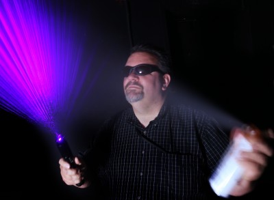 Sheldon Zimmerman, a Naval Surface Warfare Center Dahlgren Division (NSWCDD) laser engineer, demonstrates a laser typically used as an astronomy aid. It has a purple wavelength of 445 nanometers, and Zimmerman performed hazard analysis on the system. He recently received an international award from the International Electrotechnical Commission (IEC). The honor, called the 1906 Award, commemorates the IEC's year of foundation and is presented to IEC experts around the world with recent work that advanced electro technology standardization and related technologies. (U.S. Navy photo by Elliott Fabrizio/Released)