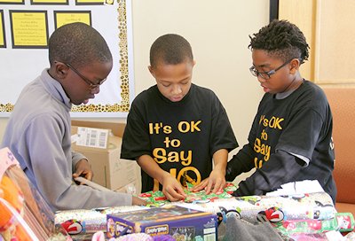 Berry Elementary School fifth graders Reginald Alexander, Michael Parham and Kylin Hertz wrap gifts as part of the school’s Five Days of Giving event.