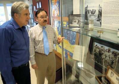 Udo Goff - a Naval Surface Warfare Center Dahlgren Division (NSWCDD) defense contractor and avid collector of World War II artifacts - explains the unique histories behind various Normandy D-Day invasion items to Jon Dachos, an NSWCDD Human Systems Integration lead engineer. Goff's D-Day collection is on display at the command's Electromagnetic and Sensor Systems Department lobby until June 12. The retired Navy commander is also exhibiting Battle of Midway artifacts at the Center for Surface Combat Systems and AEGIS Training and Readiness Center lobby until June 10. This is the third year that Goff displayed his personal collection at Dahlgren in commemoration of the invasion of Normandy and the Battle of Midway - major turning points for the U.S. military and allied forces during World War II. (U.S. Navy photo by John Joyce/Released)