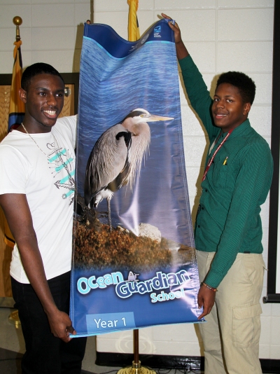 North Point High School Ocean Guardian club members William Bolton, left, and Cameron Young, right, accept a banner on Oct. 29 that designates the school as the first National Oceanic and Atmospheric Administration (NOAA) Ocean Guardian School in Maryland. The club has more than 30 student members and was recognized for their conservation and restoration projects. North Point is the first school in Maryland to be recognized through the program.