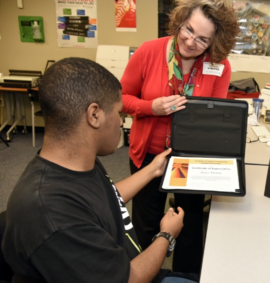 Bryce Demby, Interactive Media Production student at Robert D. Stethem Educational Center, receives a certificate of appreciation from Mediation Center Coordinator Julie Walton for his design of the center's logo.