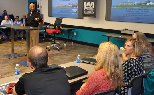 DAHLGREN, Va. - Rear Adm. Jesse Wilson, Naval Surface Force Atlantic commander, emphasizes the importance of innovating to the strategic environment as he spoke to a group of civilian technologists and military officers at the first in a series of Surface Warfare Innovation Workshops held at the Navy's newest Innovation Lab. Naval Surface Warfare Center Dahlgren Division (NSWCDD) and the Navy War College co-sponsored the event that encouraged NSWCDD scientists and engineers to throw away the rule book as they brainstormed to solve future warfighting scenarios. "The workshop enabled Navy leadership to share current and future Fleet concerns with our new and mid-career personnel to develop united, focused, and creative solutions," said NSWCDD I-Lab Director of Innovation Nelson Mills. (U.S. Navy photo/Released)