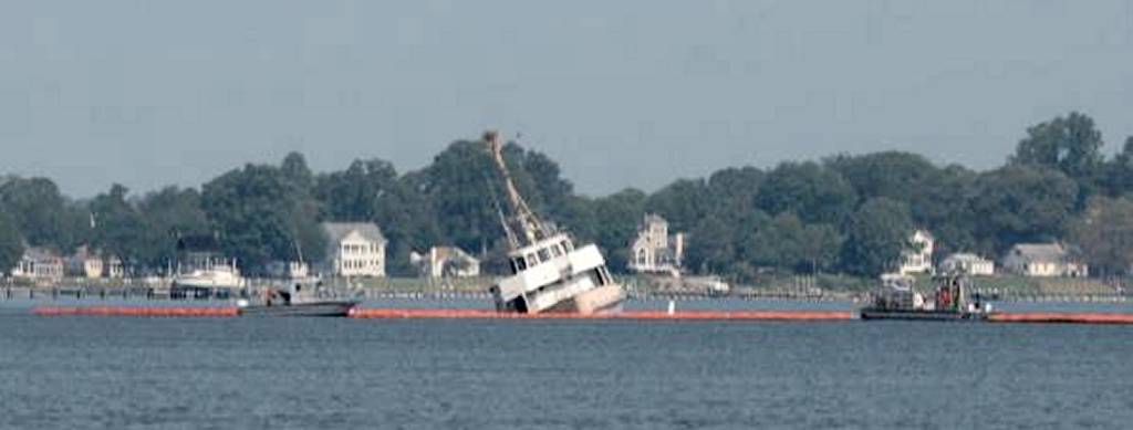PATUXENT RIVER, Maryland (Aug. 28, 2018) --- Boats from the NAS Patuxent River Port Operations Division deploy a 1000-foot boom around a civilian-owned YP craft found to be leaking fuel in the Patuxent River. NAS Patuxent River Port Operations, in conjunction with U.S. Coast Guard personnel, have been monitoring the partially submerged civilian craft for leakage since Aug. 21, and deployed a containment boom when a fuel sheen was seen around it at 7:15 a.m. Aug. 28. U.S. Navy photo (Released) 180828-NJP566-006.